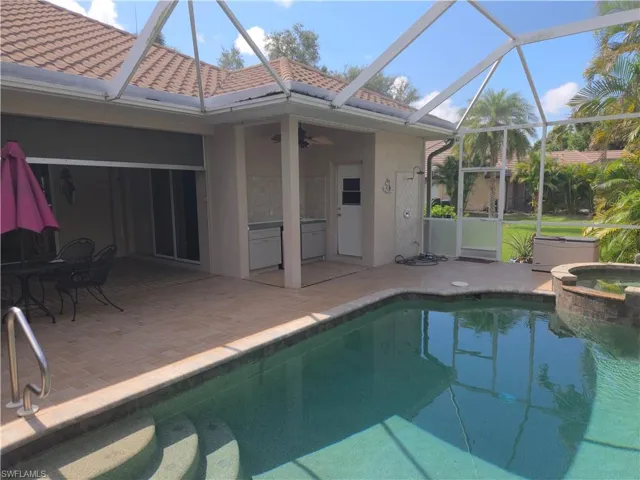 View of swimming pool featuring a patio area, a ceiling fan, a pool with connected hot tub, and glass enclosure