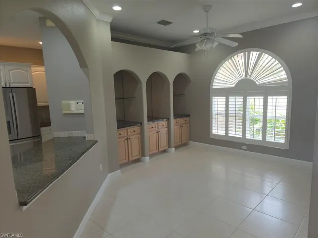 Unfurnished living room with a ceiling fan, ornamental molding, recessed lighting, arched walkways, and light tile patterned floors