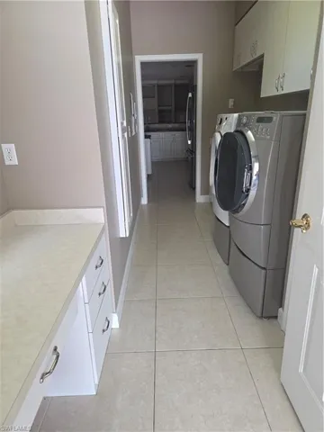 Laundry room with cabinet space, separate washer and dryer, and light tile patterned floors