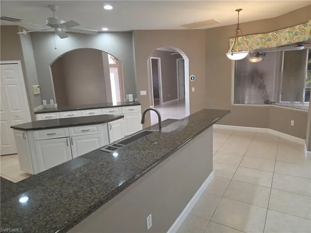 Kitchen featuring light tile patterned flooring, arched walkways, recessed lighting, white cabinets, and ceiling fan