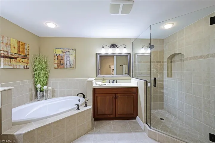 Bathroom featuring tile patterned floors, separate shower and tub, and vanity
