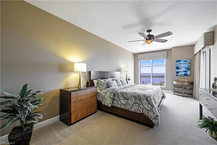 Carpeted bedroom featuring ceiling fan and a water view