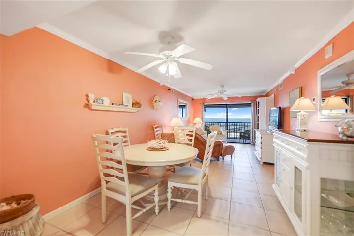 Living room with crown molding, light tile patterned floors, and ceiling fan