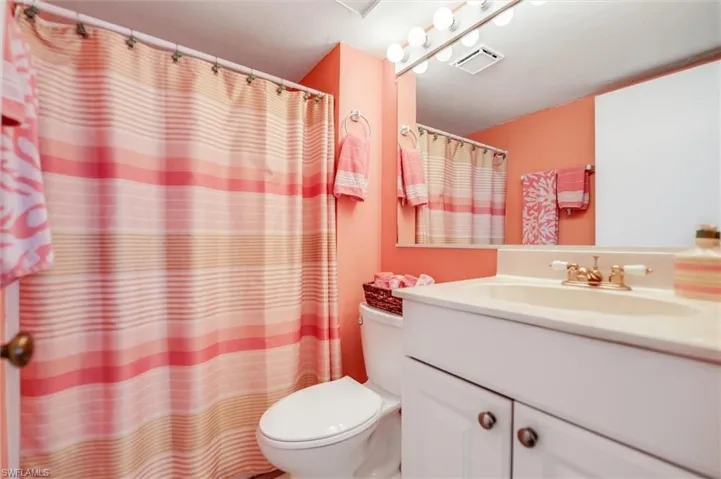 Bathroom featuring vanity, stacked washer and clothes dryer, and toilet