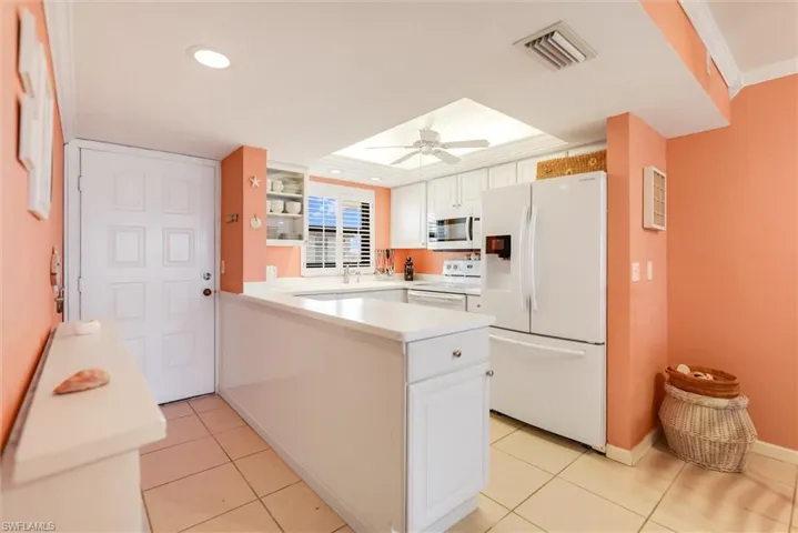 Kitchen featuring white cabinetry, light tile patterned floors, ceiling fan, ornamental molding, and white appliances
