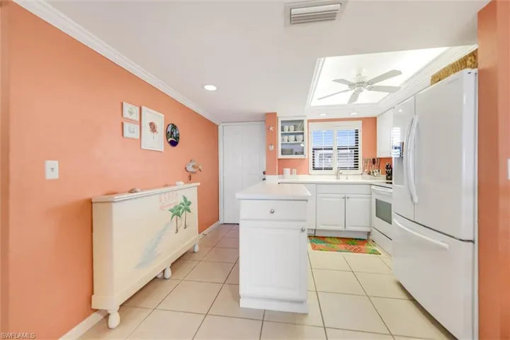Dining room with crown molding, ceiling fan, and light tile patterned floors