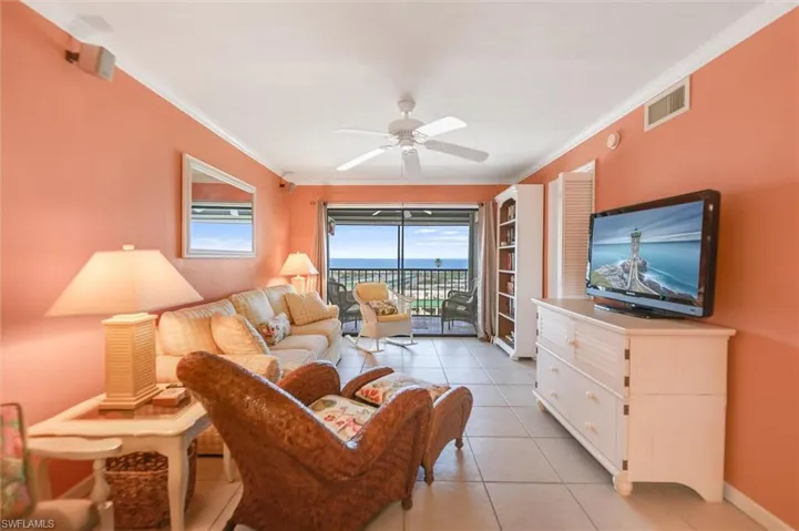 Tiled living room with crown molding and ceiling fan