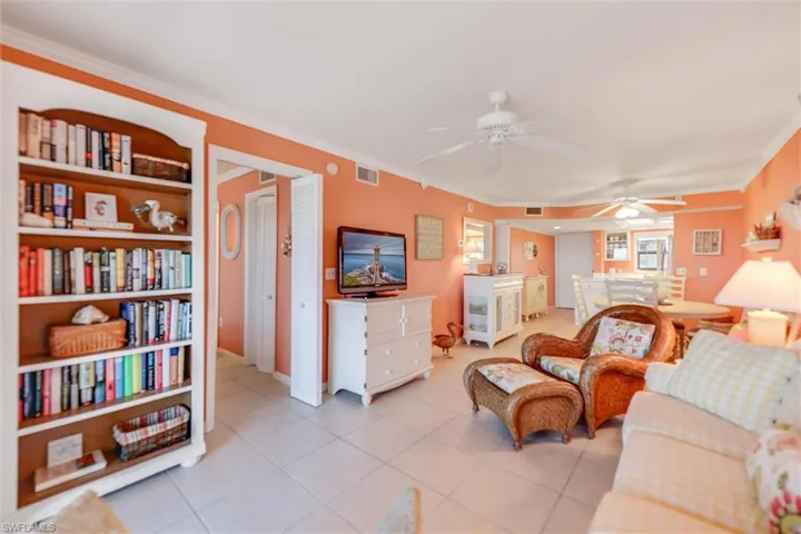 Tiled living room featuring ceiling fan and ornamental molding