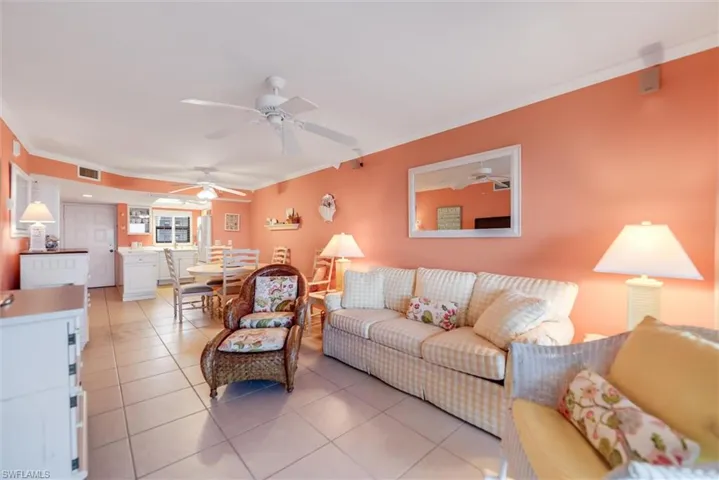 Tiled living room with ornamental molding and ceiling fan