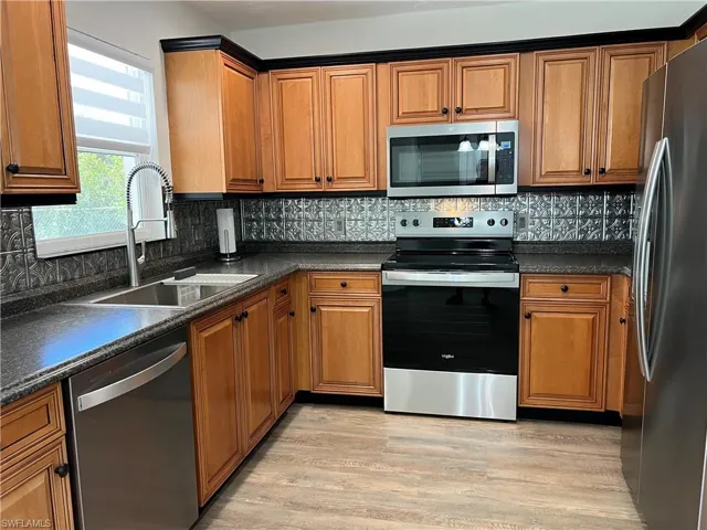 Kitchen with new stainless steel appliances, sink and faucet.