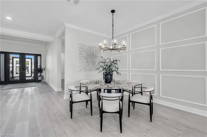 Dining area featuring crown molding, an inviting chandelier, french doors, and hardwood / wood-style flooring