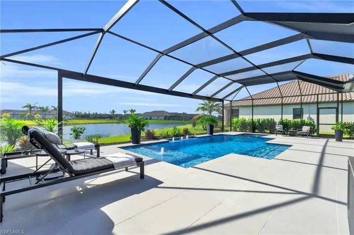 View of swimming pool featuring a patio, glass enclosure, a water view, and pool water feature