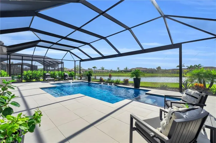 View of swimming pool with pool water feature, glass enclosure, and a patio area