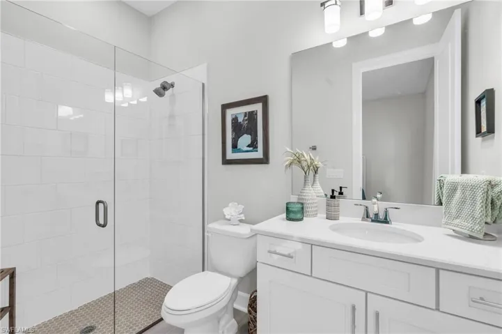Bathroom featuring a shower with shower door, vanity, and toilet