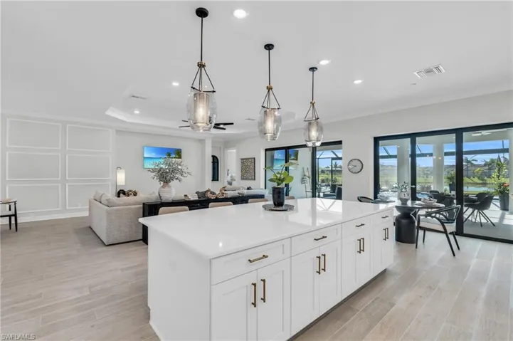 Kitchen with hanging light fixtures, french doors, white cabinetry, a center island, and light wood-type flooring