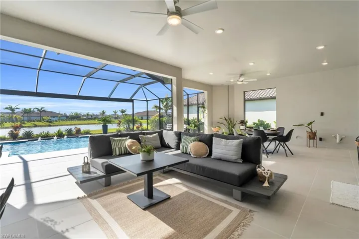 Living room featuring ceiling fan, light tile patterned floors, and a water view