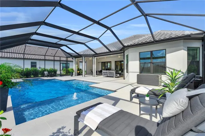 View of swimming pool featuring glass enclosure, pool water feature, and a patio area