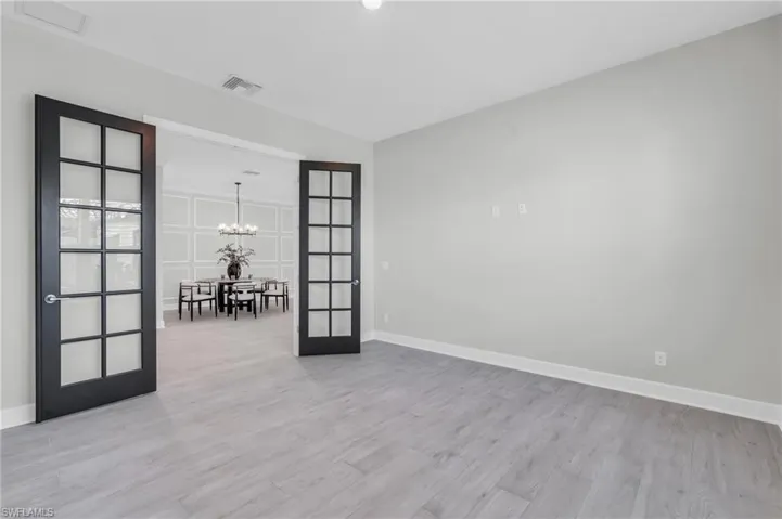 Empty room featuring vaulted ceiling, light wood-type flooring, and a chandelier