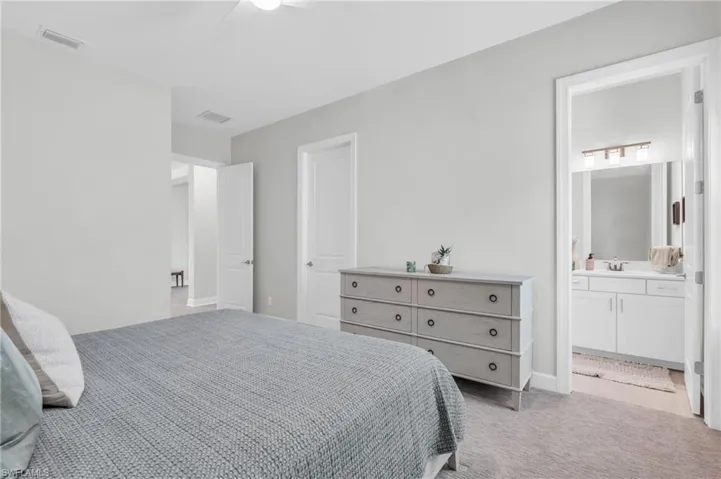 Carpeted bedroom featuring ceiling fan, ensuite bath, and sink