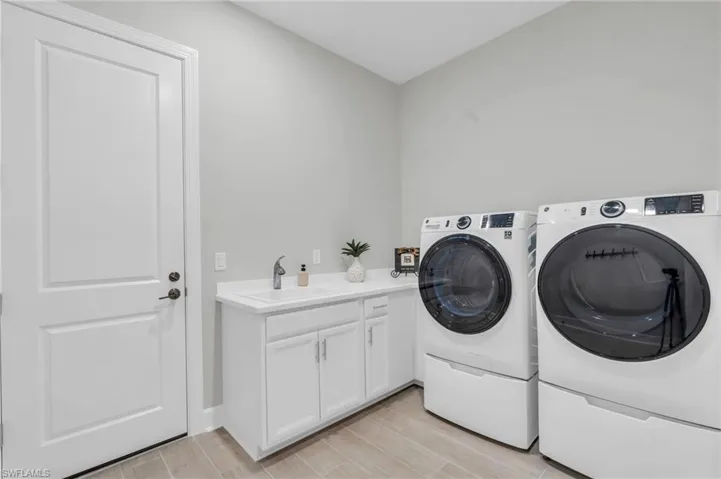 Washroom with cabinets, light hardwood / wood-style floors, sink, and washing machine and clothes dryer