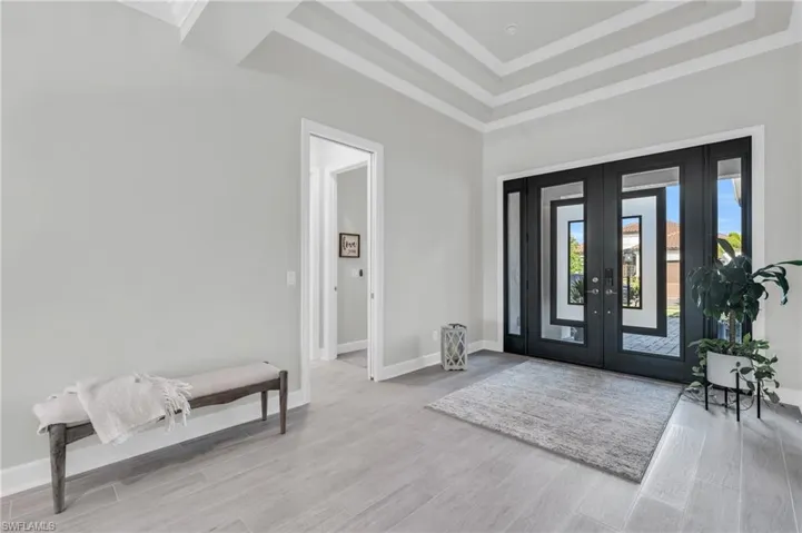 Entrance foyer featuring french doors, ornamental molding, a tray ceiling, and light hardwood / wood-style floors