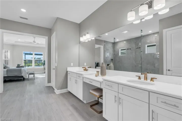 Bathroom with wood-type flooring, tiled shower, vanity, and ceiling fan