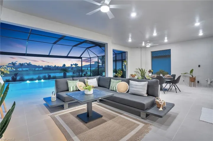 Patio terrace at dusk with a lanai, ceiling fan, and outdoor lounge area