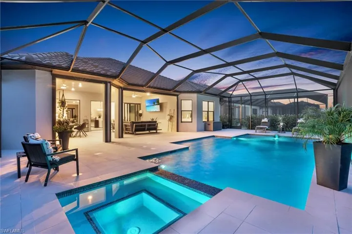 View of swimming pool with glass enclosure, an in ground hot tub, and a patio area