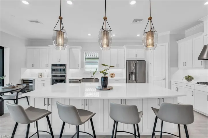 Kitchen with appliances with stainless steel finishes, decorative backsplash, decorative light fixtures, sink, and a spacious island
