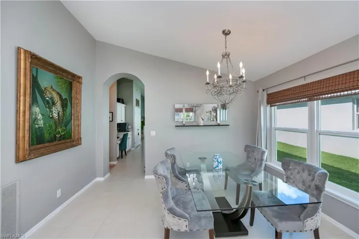 Dining space with arched walkways, a chandelier, and vaulted ceiling