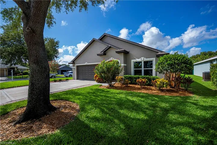 Ranch-style house featuring stucco siding, a front lawn, driveway, and a garage