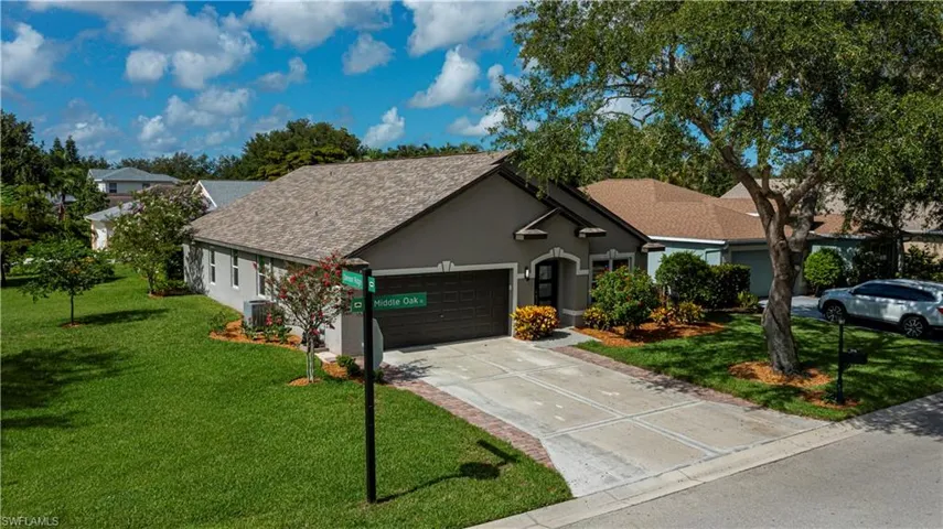 View of front of home featuring a garage, stucco siding, a front lawn, concrete driveway, and roof with shingles