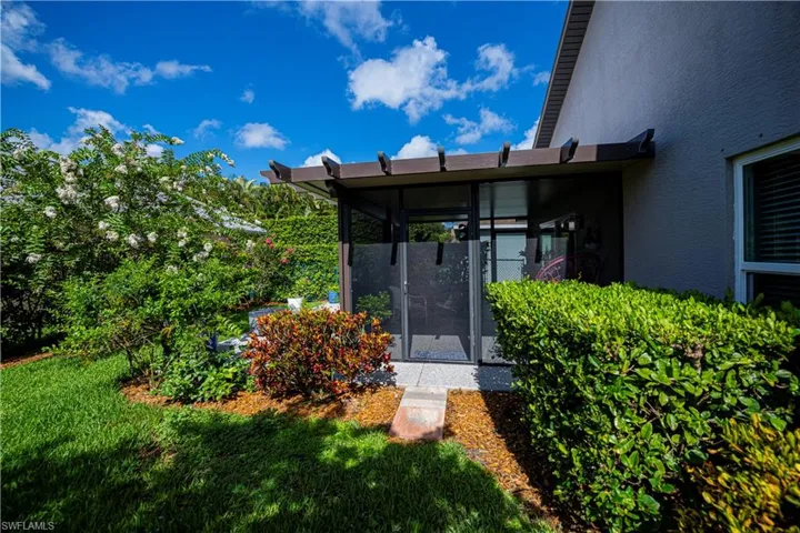 View of exterior entry with stucco siding and a lawn