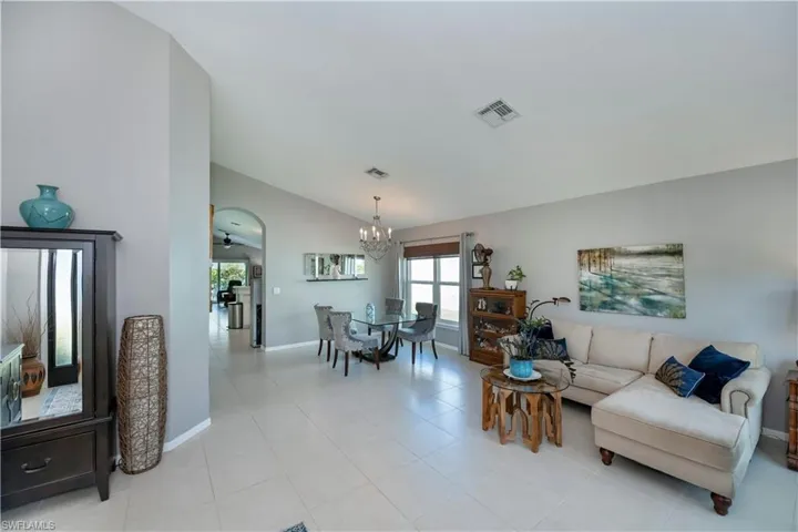 Living area with vaulted ceiling, a chandelier, arched walkways, and light tile patterned flooring