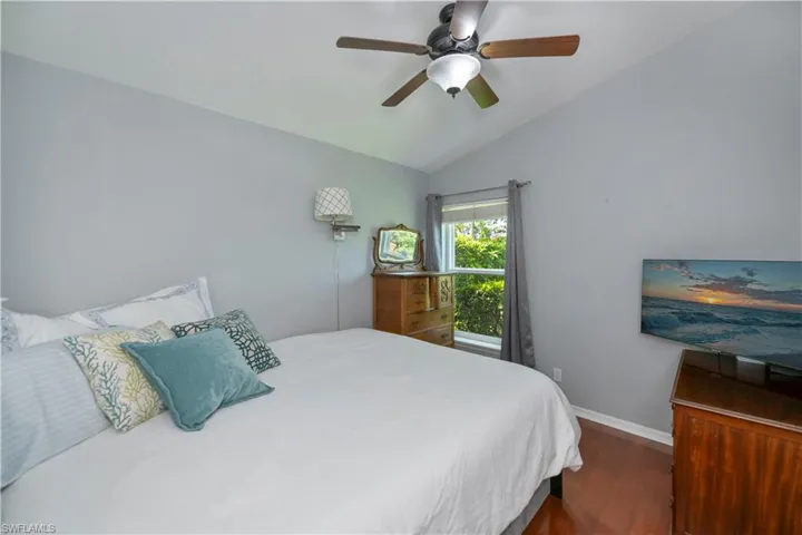 Bedroom with wood finished floors, lofted ceiling, and a ceiling fan