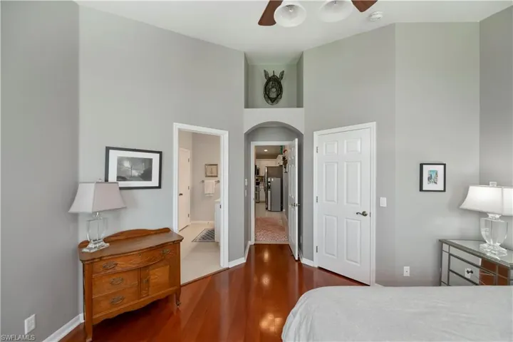 Bedroom featuring arched walkways, wood finished floors, a towering ceiling, and ceiling fan