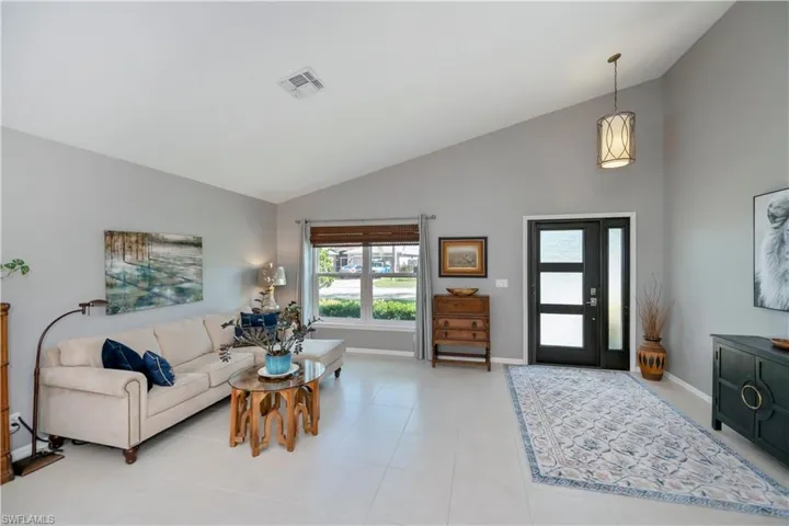 Living area with high vaulted ceiling and light tile patterned floors