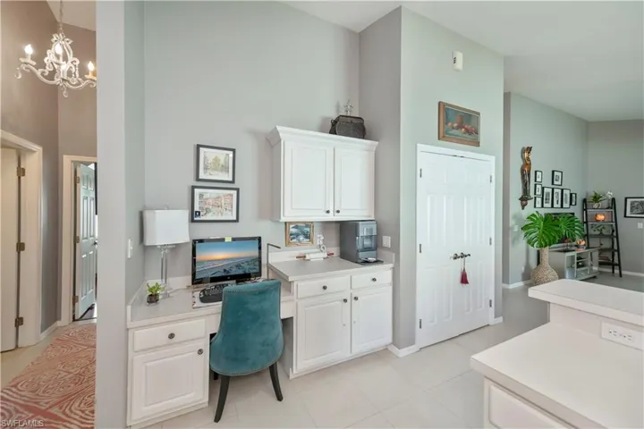 Office space featuring a chandelier, light tile patterned floors, built in desk, and a high ceiling