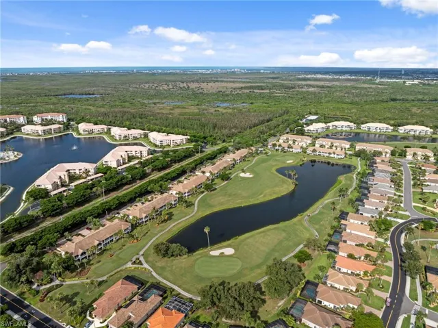Aerial perspective showcasing a residential community with golf course frontage, multiple water features, and lush landscaping