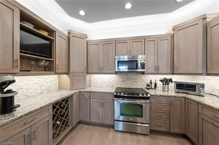 Sophisticated kitchen featuring custom cabinetry with recessed panel doors, granite countertops, and a coordinating tile backsplash