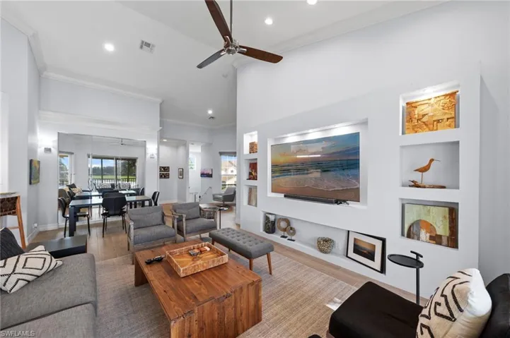 Open-concept living area featuring soaring ceilings with ceiling fan, recessed lighting, and abundant natural light from multiple windows