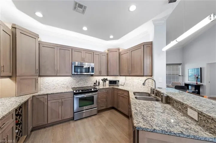 Contemporary kitchen featuring wood-finish cabinetry, granite countertops, a built-in stainless steel microwave, and a stainless steel range