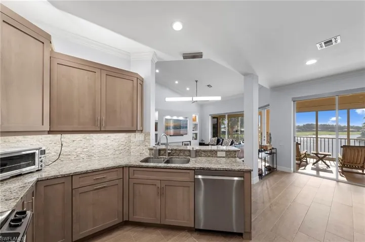 Kitchen with light wood-finish cabinetry, granite countertops, and a tile backsplash
