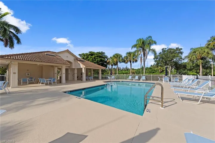 Outdoor swimming pool featuring a tanning ledge and perimeter fencing