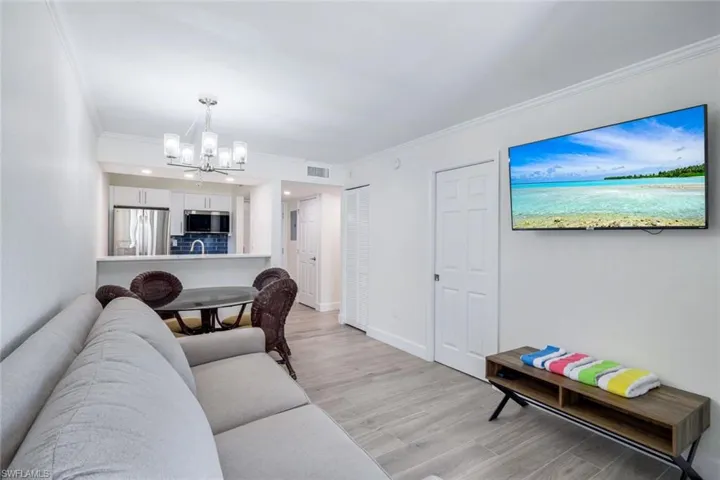 Living area with a chandelier, light wood-style flooring, and ornamental molding