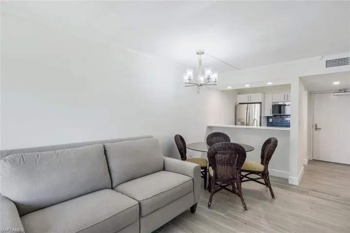 Living area with a chandelier, ornamental molding, light wood-style floors, and recessed lighting