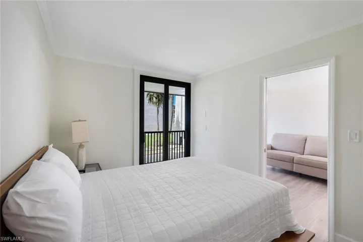 Bedroom with ornamental molding, wood finished floors, and access to outside