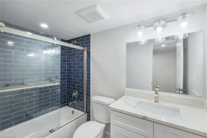 Full bathroom featuring vanity, shower / bath combination with glass door, and recessed lighting