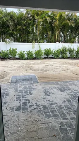 Backyard view of covered lanai with pavers