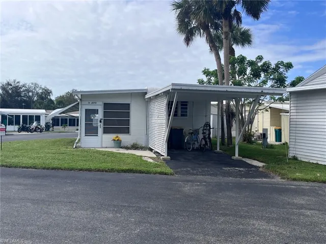 Manufactured / mobile home with a front yard and a carport